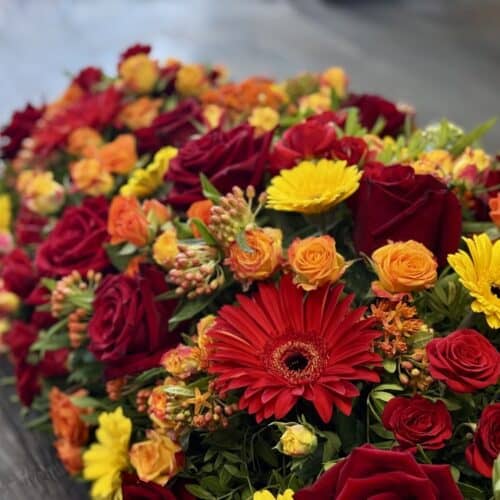 Coussin de deuil Hommage Éclatant aux fleurs rouges, jaunes et orange